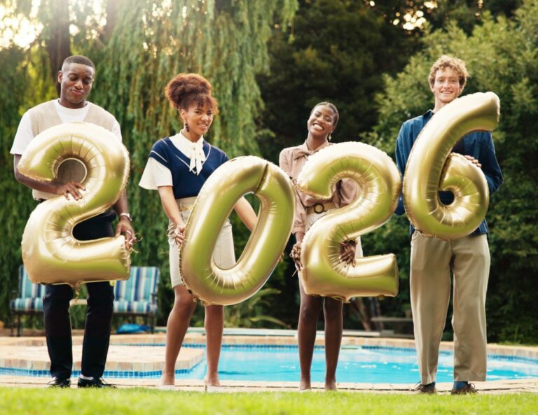 Quatre personnes souriantes tenant des ballons en forme de chiffres 2026 près d'une piscine.